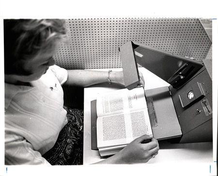 A photograph showing a student demonstrating a reading machine in the Pearson Hall reading lab.