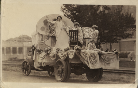 A VEISHEA parade float from the 1922 celebration. Two students are seen painting, while one is posing.