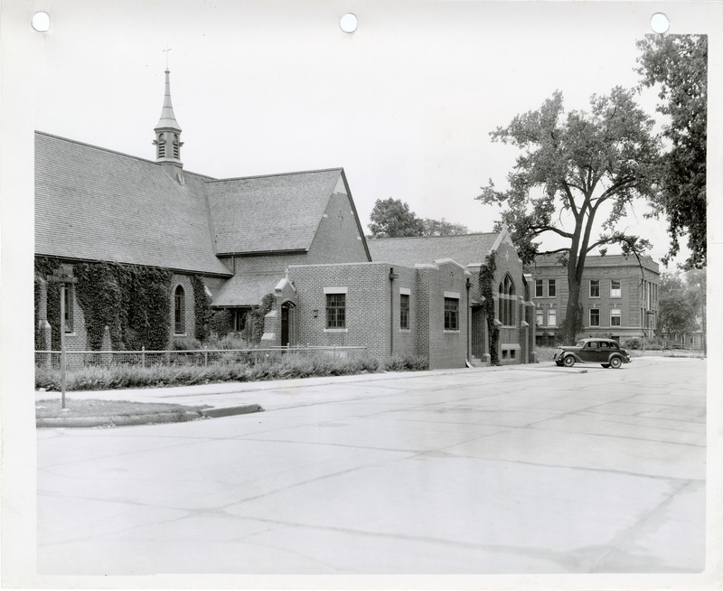 Photograph of buildings and a car parked in the parking area of the Mason City business district