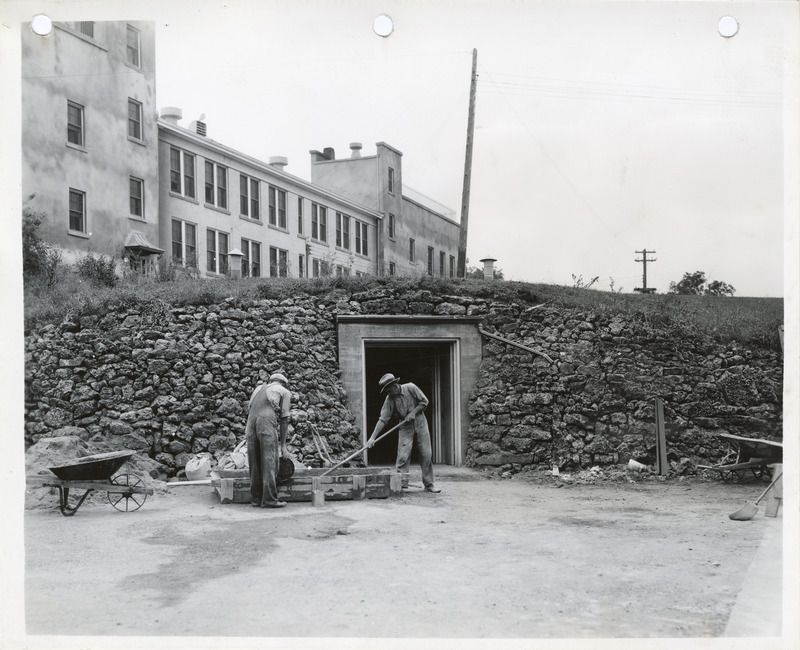 Photograph of two men working in front of the root cellar in Sunnycrest Sanitarium
