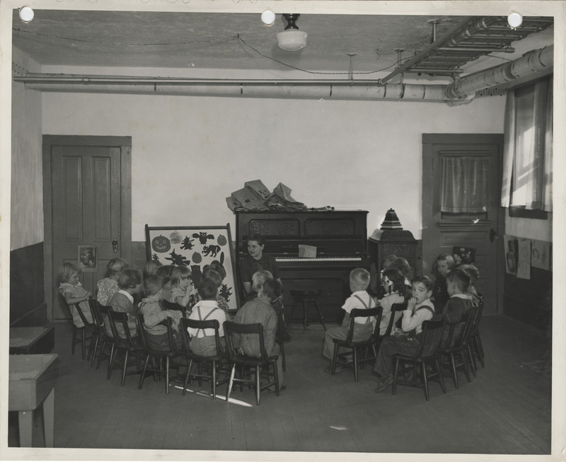 Photograph of a teacher and students in a grade school classroom in Columbus Junction