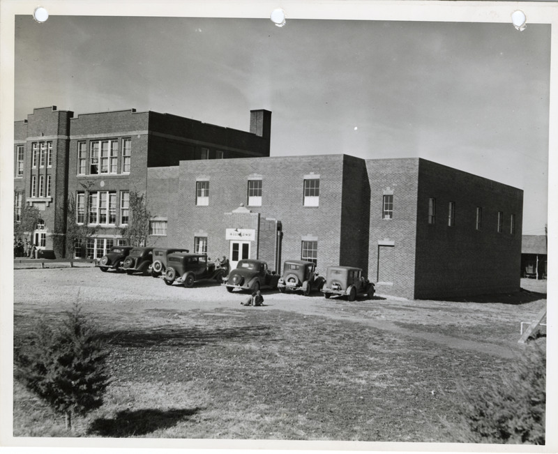 Photograph of cars parked outside the high school gym in Cedar