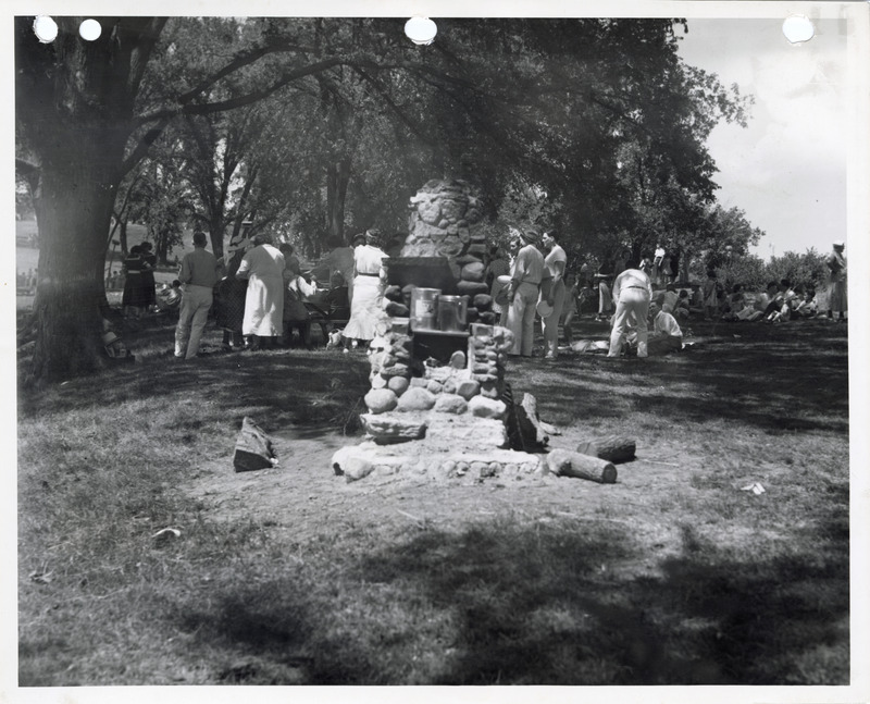 Photograph of people standing around an outdoor fireplace at Edmundson Park in Oskaloosa