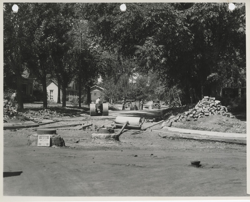 Photograph of people lowering a street grade and paving it with bricks in Albia