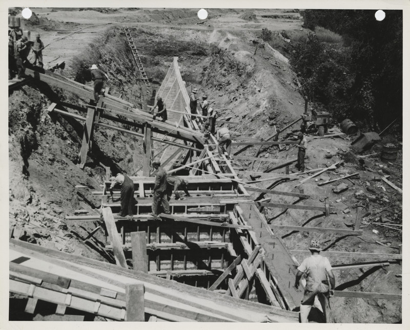 Photograph of people pouring concrete for a river wall on the Raccoon River in Des Moines