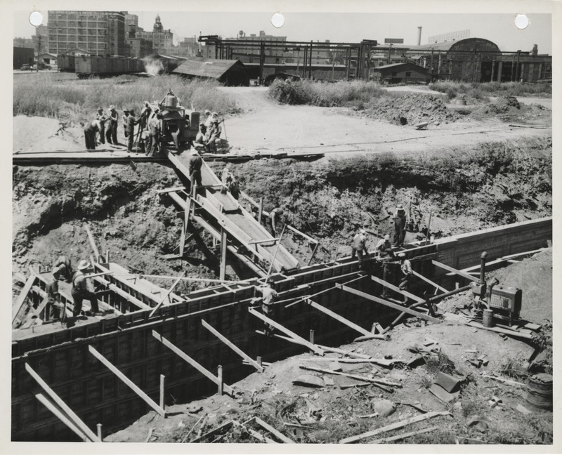 Photograph of people pouring concrete for a river wall on the Raccoon River in Des Moines