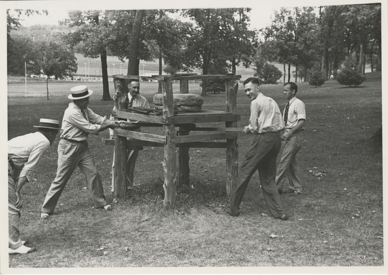 Photograph of five people around a millstone