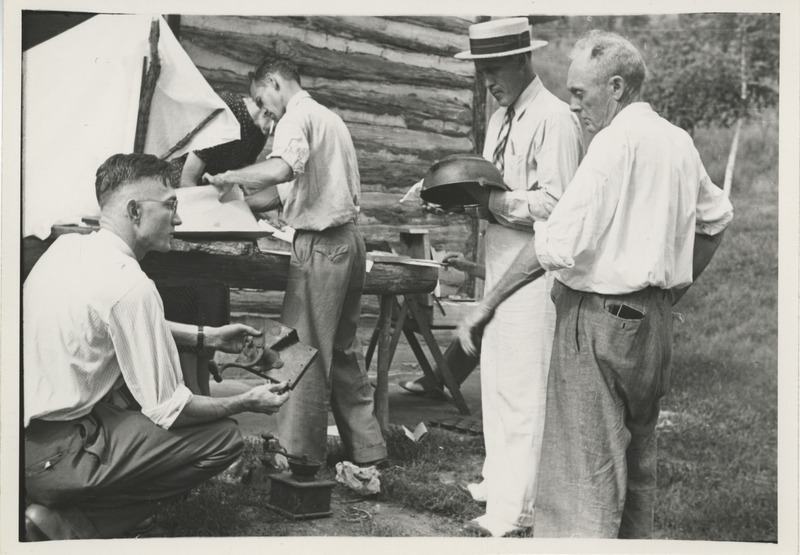 Photograph of people inspecting vintage utensils