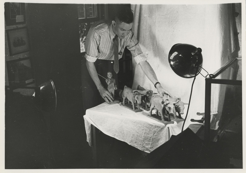 Photograph of a person with models of oxen