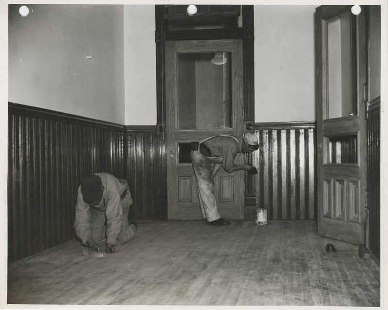Photograph of people refinishing the wood paneling and floor of the county courthouse in Marshalltown