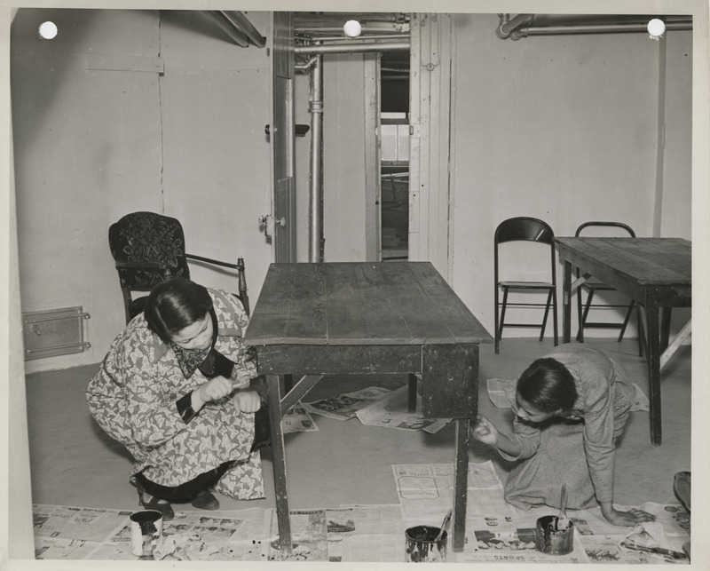 Photograph of two people painting a table at the East Side Community House in Des Moines