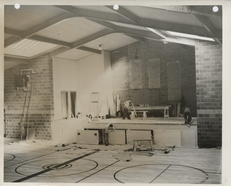 Photograph of people constructing a school building gymnasium addition in Colfax