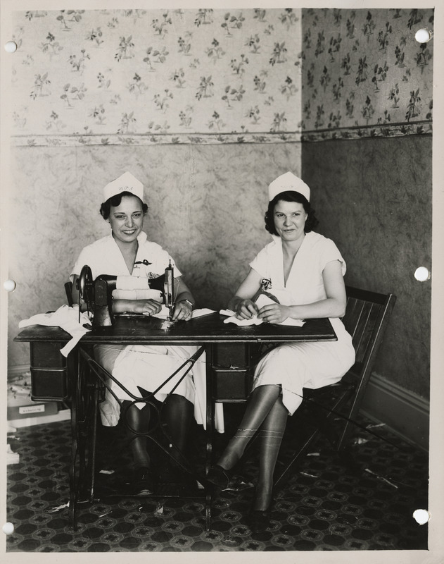 Photograph of two people sitting at a sewing machine in Sidney