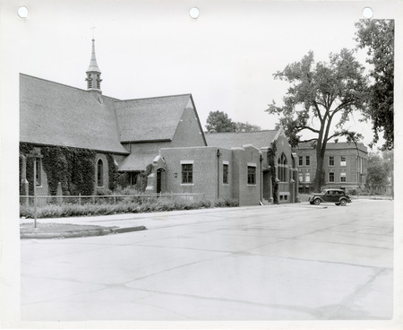 Photograph of buildings and a car parked in the parking area of the Mason City business district