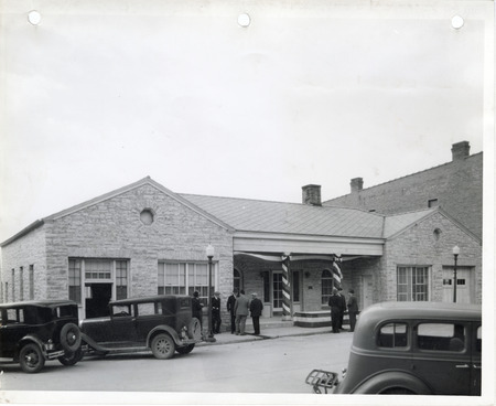 Photograph of cars parked outside and people standing in front of the Memorial Building in Cascade