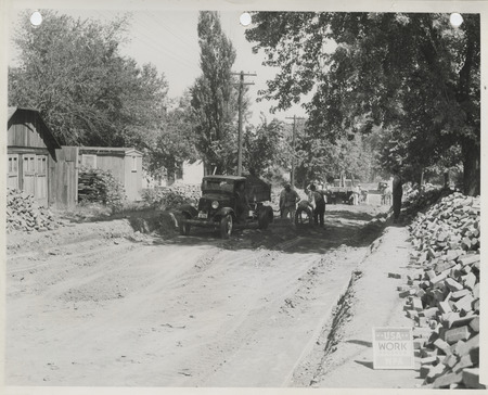 Photograph of people lowering a street level and paving it with bricks in Albia