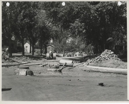 Photograph of people lowering a street grade and paving it with bricks in Albia