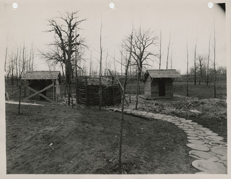 Photograph of latrines, crib for storing wood shavings and sidewalk in the Lewis and Clark State Park