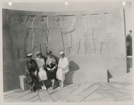 Photograph of four people sitting in front of the Lewis and Clark monument in Council Bluffs