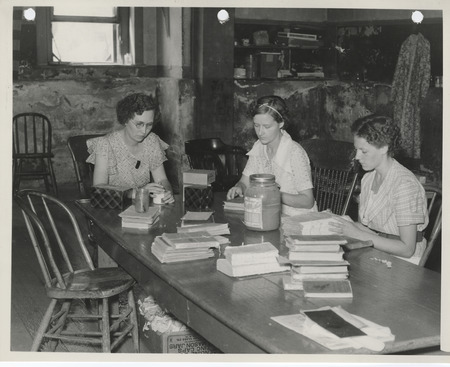 Photograph of people mending and indexing school books in Albia