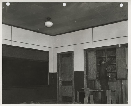 Photograph of a person painting cabinets at a school in Gillett Grove