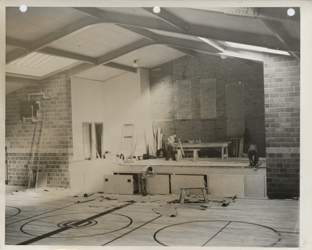 Photograph of people constructing a school building gymnasium addition in Colfax